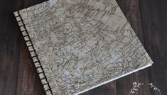 an old map is laying on top of a wooden table next to some dried flowers