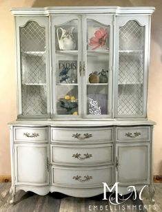 a white china cabinet with glass doors and drawers