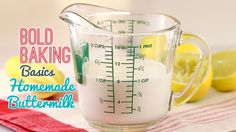 a glass measuring cup filled with liquid next to lemons and a red towel that says bold baking basics homemade buttermilk