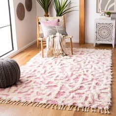 a living room with a rug, chair and potted plant