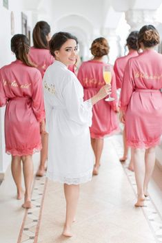 a woman in pink robes holding a glass of wine