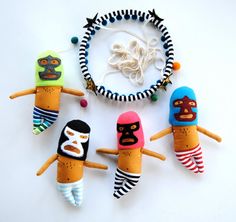 four toy figures hanging from a string on a white surface with bead necklaces around them