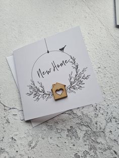 a new home card with an ornament hanging from it's side on top of a piece of paper