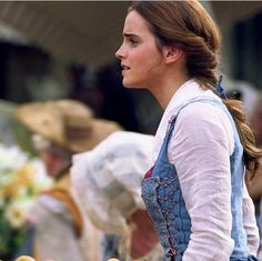 a woman in an apron is standing by some fruit