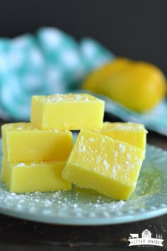 four pieces of yellow cake sitting on top of a glass plate with powdered sugar