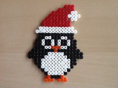 a black and white penguin with a red hat on it's head is made out of legos