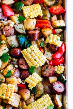 a casserole dish filled with grilled vegetables and corn on the cob