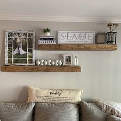 a living room filled with furniture and two wooden shelves above the couch, along with pictures on the wall