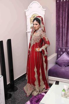 a woman in a red and gold bridal gown standing next to a purple couch