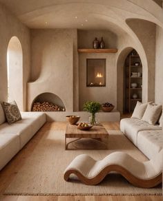 a living room filled with white couches and a table in front of an open fire place