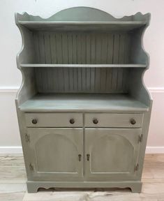 an old china cabinet painted gray with white trim and knobs on the bottom shelf