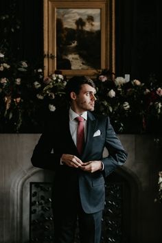 a man in a suit standing next to a fireplace