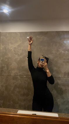 a woman taking a selfie in front of a mirror with her cell phone up to her face