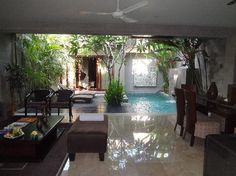 a living room filled with furniture next to a swimming pool in the middle of a house