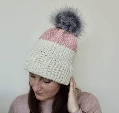 a woman wearing a pink and white hat with a grey pom - pom