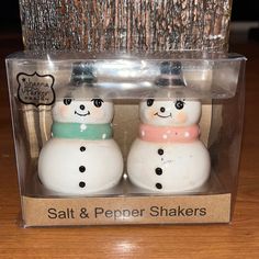 two salt and pepper shakers with snowmen on them in a clear plastic box