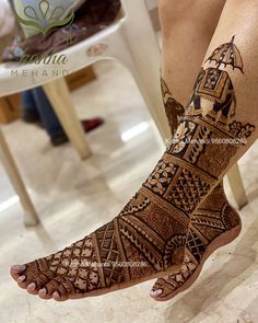 a woman's feet with hennap and tattoos on her legs in front of a table