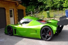 a green sports car parked in front of a garage