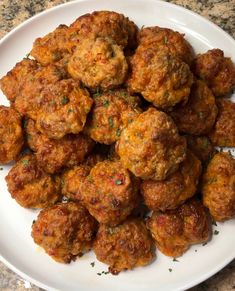 a white plate topped with meatballs on top of a marble countertop covered in parsley