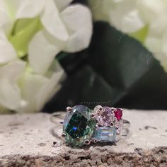 two different colored stones sitting next to each other on a stone surface with flowers in the background