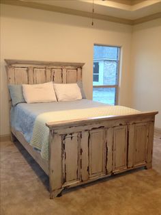 a bed sitting in a bedroom next to a window with a wooden headboard and foot board