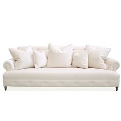 a white couch with lots of pillows on it's back and side cushions in the middle