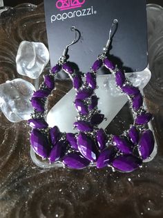 a pair of purple earrings sitting on top of a table