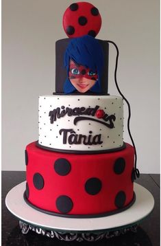 a three tiered cake decorated with ladybug and polka dot designs on top