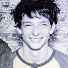 an old black and white photo of a young man in front of a brick wall