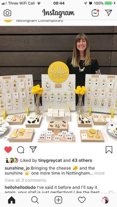 a woman standing in front of a table filled with yellow flowers and other items for sale