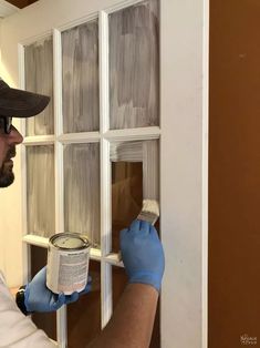 a man in blue gloves painting a window with white paint on the outside and inside