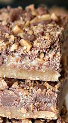 three pieces of chocolate peanut butter fudge bars stacked on top of each other with nuts