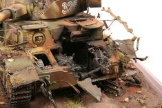 a toy army tank sitting on top of a pile of dirt