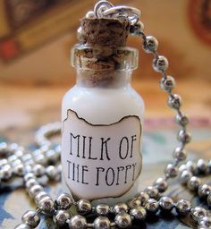 a bottle necklace with a message on it that says milk of the potty and is attached to a ball chain