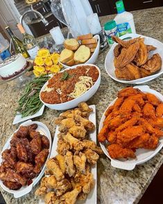 several plates filled with different types of food on a counter top next to bottles of wine