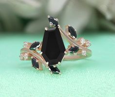 a black diamond ring sitting on top of a green surface with white flowers in the background