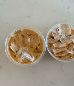 two plastic cups filled with ice and brown liquid