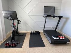 a home gym with treadmills, exercise mats and computer monitor on the wall