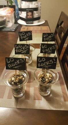 there are some rocks in small bowls on the table with name tags attached to them