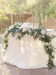 a table with flowers and greenery is set up for an outdoor wedding reception in the woods