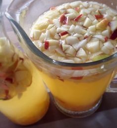 a pitcher filled with liquid next to an apple