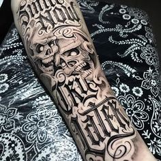 a man's arm with a skull and lettering tattoo on the left side of his arm