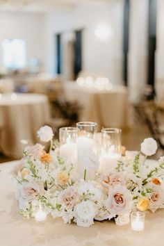 a centerpiece with candles and flowers on a table in a banquet or wedding reception