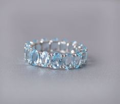 an aqua blue ring is shown on a gray surface, with diamonds around the band