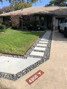 a driveway with stepping stones in front of it and a yard sign on the side