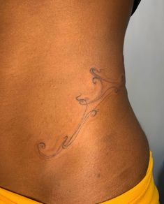 a woman's lower back with a small tattoo on her left side and the bottom part of her stomach