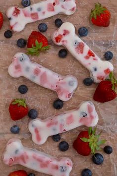 strawberries and blueberries are arranged in the shape of bone shaped dog bones with white icing