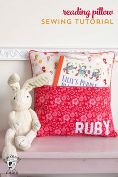 a stuffed rabbit sitting on top of a pillow next to a red pillow cover with the words ruby printed on it