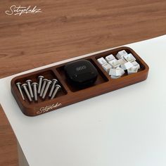 there is a wooden tray with keys and other items in it on top of a table