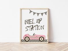 a framed poster with the words fuel up station in black and white, hanging on a wall